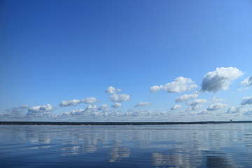 seascape, sea reflects blue sky with clouds