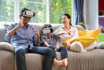 Obraz premium Father, mother and sons playing video games with virtual reality glasses - Father and sons having fun with new technology console online