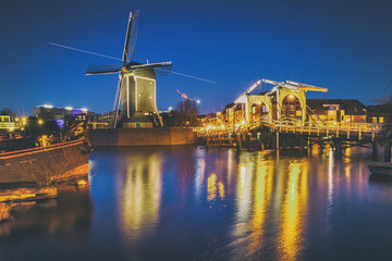 Fototapeta na wymiar Cityscape - evening view of the city canal with drawbridge and windmill, the city of Leiden, Netherlands.