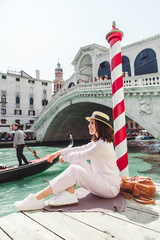 woman sitting near rialto bridge in venice italy looking at grand canal with gondolas © phpetrunina14