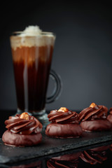  Chocolate dessert with hazelnut and coffee with cream on a black background.