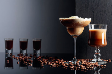 Coffee cocktails and coffee liquor on black reflective background.