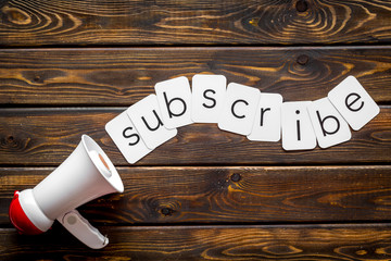 loudspeaker and subscribe text for announcement on wooden background top view