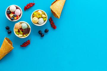 Gelato, waffle cone, berries, chocolate on blue background top view copyspace