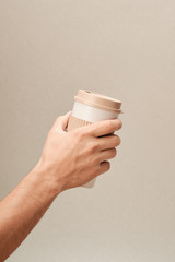 Eco Coffee Cup in Hand on Beige Background