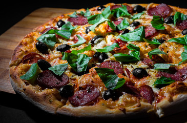 Pepperoni Pizza with Mozzarella cheese, salami, olive, pepper, Spices and Fresh basil. Italian pizza on Dark grey black slate background