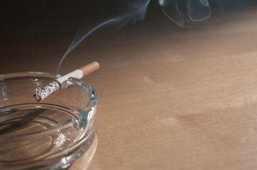 Burning cigarette in ashtray on the table