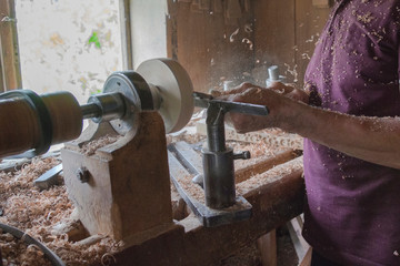 Elderly man works on a carpentry machine, retro style, dust and shavings on a table