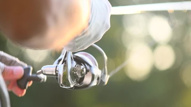 River fishing. Fisherman with a fishing rod on the river bank. Spinning. Fisher man catches a fish. Slow motion 4K UHD video footage. 3840X2160