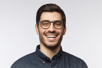 Obraz premium Laughing man with trendy haircut and glasses isolated on gray background