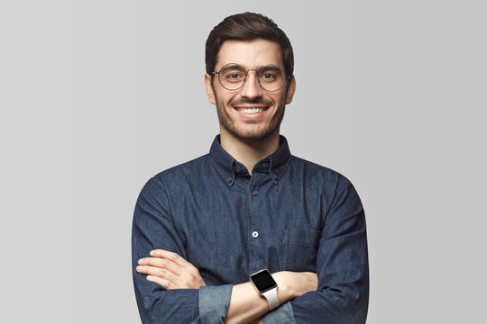 Smiling Handsome Man Standing With Crossed Arms Isolated On Gray