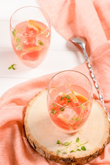 Healthy summer drink grapefruit lemonade with thyme in glasses with ice on a wooden surface.