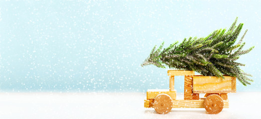 Christmas background. Wooden car carrying christmas tree on a snowy landscape