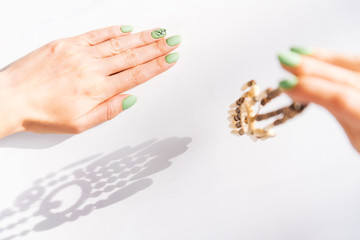 Obraz premium Woman’s hands with beautiful green manicure holding wooden necklace.