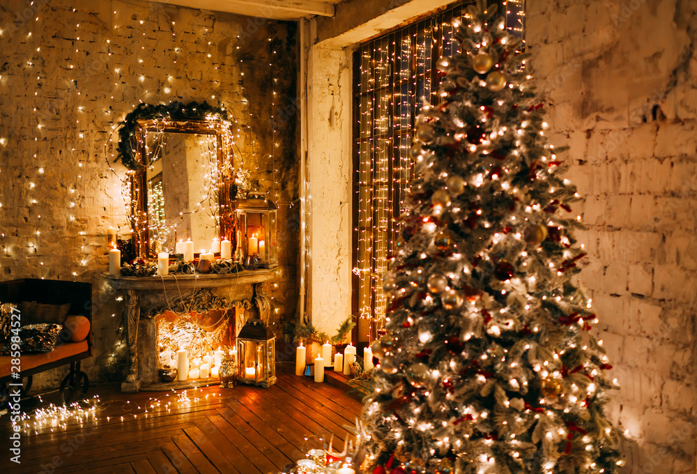 Wall mural warm cozy magic evening in luxury old Christmas living room fairy tale interior design, fireplace, windows, Xmas tree decorated by lights, gifts, candles, lanterns, garland lighting.New year holiday