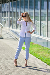 Street style fashion - lady in white shirt and boyfriend jeans walking along business centre