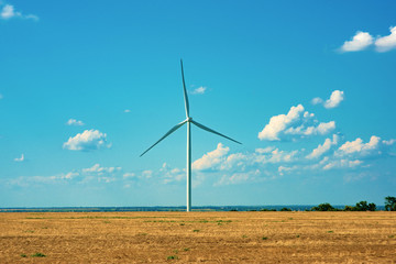 Wind generators with turbine engines and large blades. Electricity air generators are placed in the field.