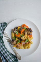 Baked young potatoes with meat and vegetables. Dark wooden background.