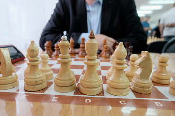 The concept of strategy and tactics of doing business. Chess pieces on the Board. Grandmaster in a jacket, with a beard sitting at the Board