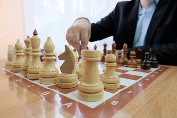 The concept of strategy and tactics of doing business. Chess pieces on the Board. A man in a jacket with a beard holding a figure in his hand