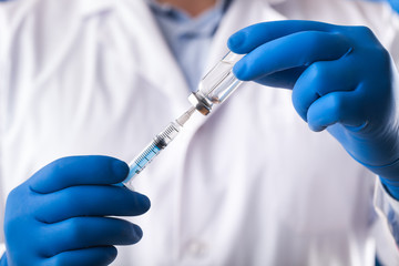 Fototapeta premium Doctor hand holds syringe and vaccine