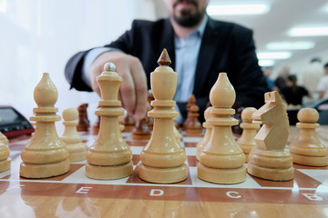 The concept of strategy and tactics of doing business. Chess pieces on the Board. A man in a jacket playing chess.