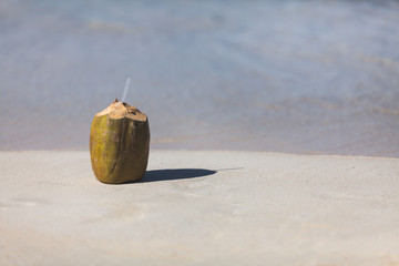 Fresh coconut on a sandy tropical beach with sea
