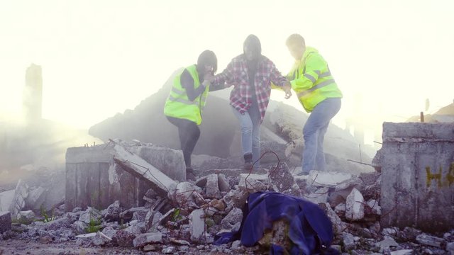portrait rescuers in uniform help the victim of the earthquake ,pulling her out from under the ruins of the house