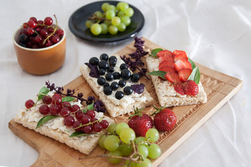 summer breakfast in bed with sandwiches with cheese and berries on diet bread