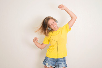 Happy teenager girl in headphones listening to music.