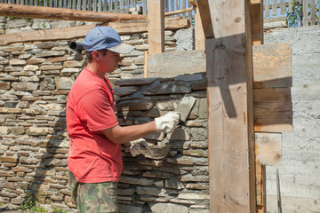man with trowel for stone wall construction.
