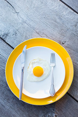 Fried egg on a white, yellow plate. Top view. Restaurant. Breakfast