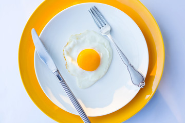 Fried egg on a white, yellow plate. Top view. Restaurant. Breakfast