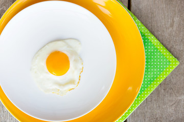 Fried egg on a white, yellow plate. Top view. Restaurant. Breakfast
