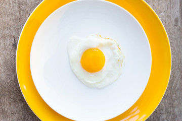 Fried egg on a white, yellow plate. Top view. Restaurant. Breakfast