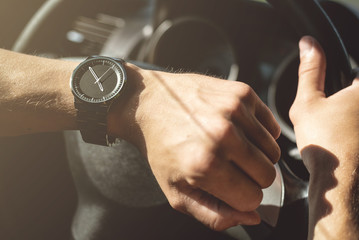 Driver is checking a time on wrist watch on his hand. - obrazy, fototapety, plakaty