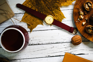 A cup of tea, nuts and croissants are on the table. Wrist Watch.