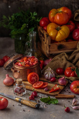 Chopped tomatoes in a copper pan with ripe tomatoes on background