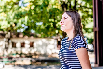 Close up portrait of a beautiful young caucasian woman smiling and looking up outdoors in a sunny day