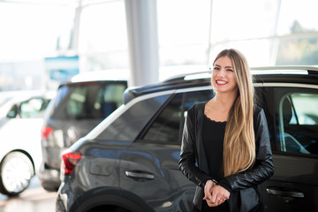 Fototapeta na wymiar Smiling woman choosing her car at a car dealer