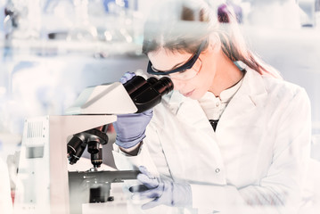 Life scientists researching in laboratory. Focused female young scientist microscoping in...