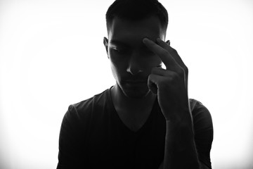 Portrait on a wide angle, the silhouette of a concentrated man, a hand at his forehead, the pose of a thinker