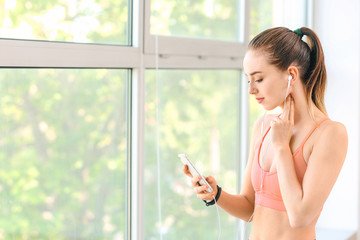 Sporty young woman checking her pulse after training in gym