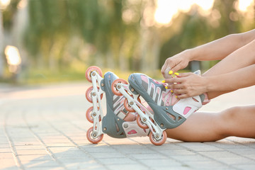 Teenage girl putting on roller skates outdoors © Pixel-Shot