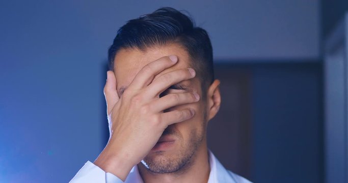 Portrait of attractive man making facepalming pose with hand. Showing an expression of dismay, exasperation, embarrassment. Businessman is disappointed and covers his face with his hand.