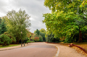 Fototapeta na wymiar Scenic alley with light posts and benches in Battersea Park in autumn season, London, United Kingdom
