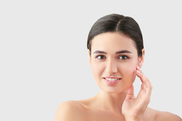 Young woman with beautiful eyebrows on light background