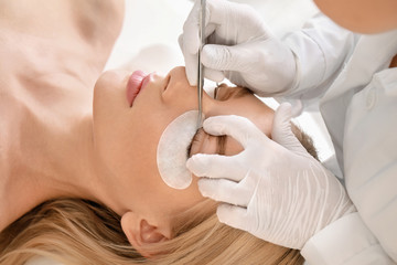 Obraz na płótnie Canvas Young woman undergoing procedure of eyelashes lamination in beauty salon