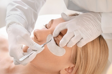 Young woman undergoing procedure of eyelashes lamination in beauty salon