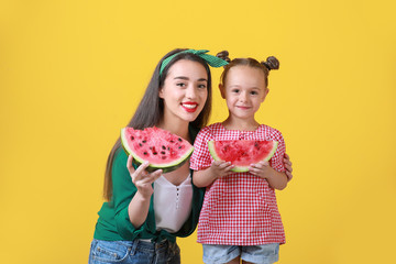 Beautiful young woman and cute girl with fresh watermelon on color background